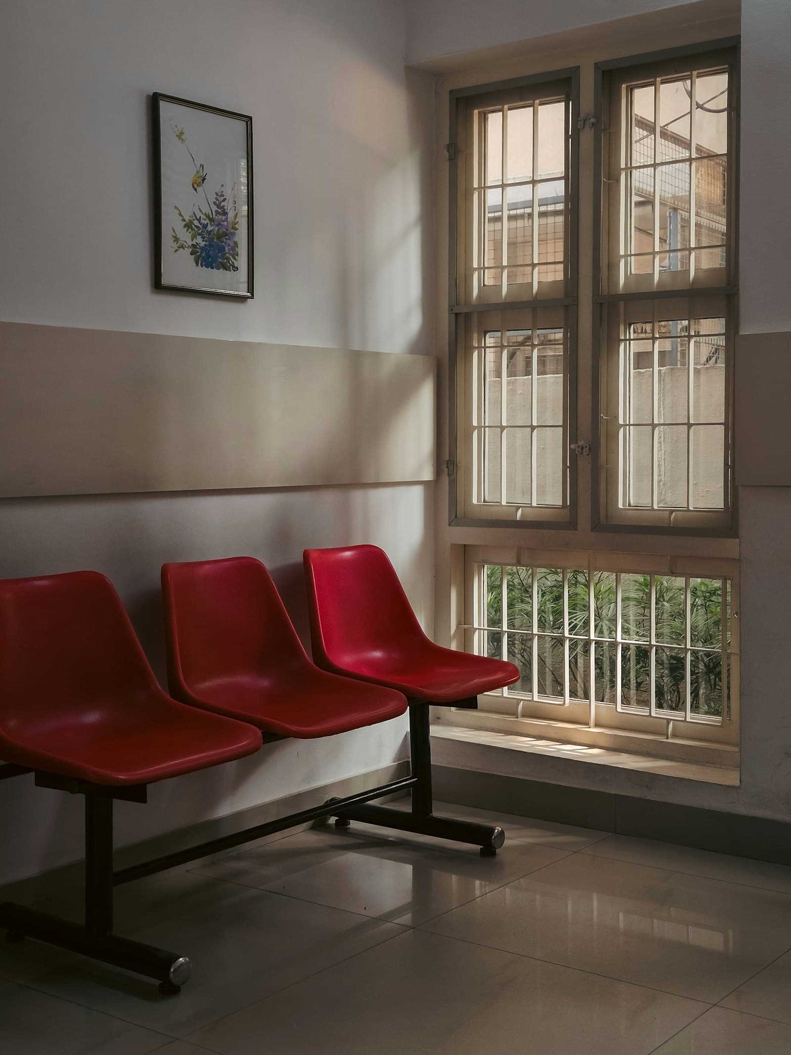 Three empty red chairs in a waiting room