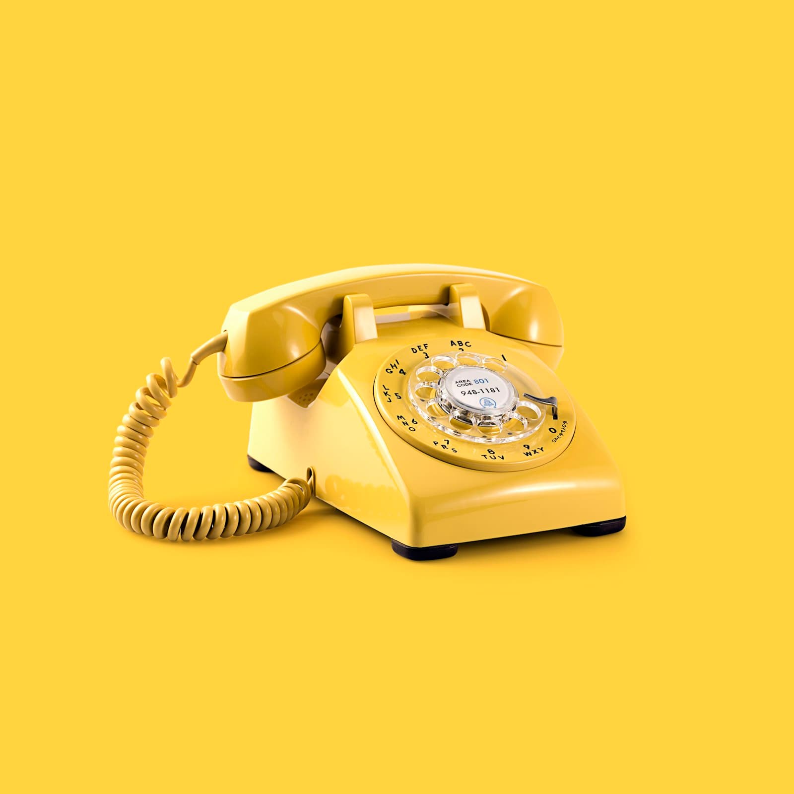 Yellow rotary telephone on a yellow background
